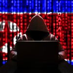 Cyber threat from North Korea. North Korean hacker at the computer, on a background of binary code, the colors of the flag of the DPRK. DDoS attack