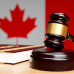 Close-up of the judge's hammer on a wooden table against the background of the Canadian flag, The concept of canadian legislation.