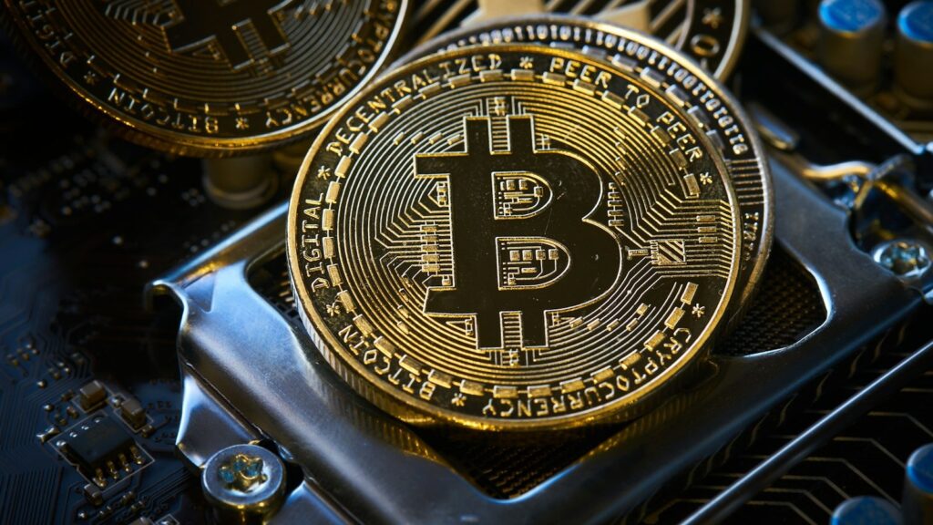 عملة بيتكوين ذهبية اللون موضوعة فوق لوحة إلكترونية لجهاز تعدين
