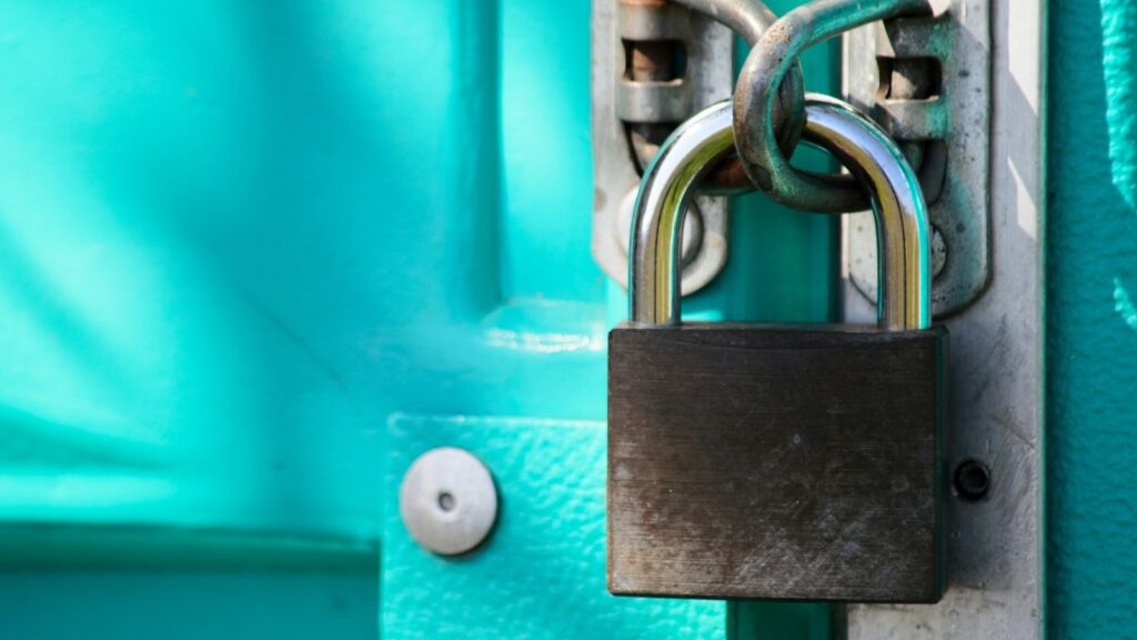 قفل معدني حقيقي مثبت على باب معدني بلون فيروزي يرمز للحفظ الآمن