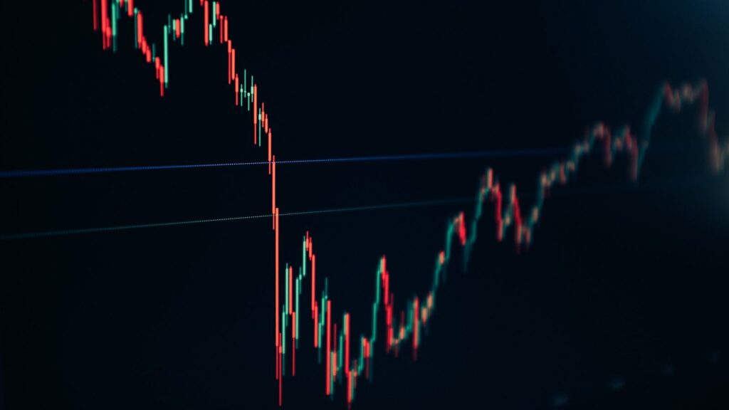 شاشة تعرض مخطط شموع يابانية حمراء وخضراء لحركة سعرية